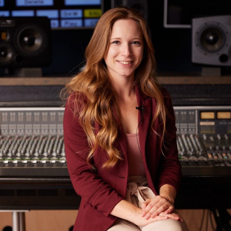 A woman sitting in front of a mixing desk.